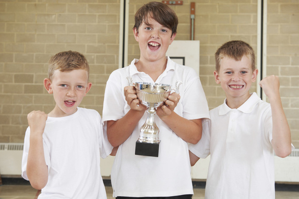 Male School Sports Team In Gym With Trophy - Foto, afbeelding