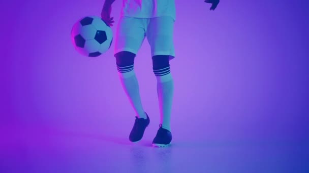 young african footballer is dribbling ball and doing keep-ups in studio, closeup of feet of player - Footage, Video