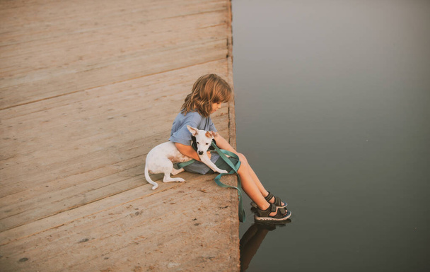Little child with dog sitting in park near water. - Fotografie, Obrázek