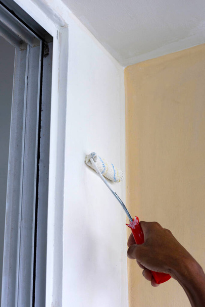 Εργάτης χέρι κρατήσει ρολό χρώμα, ζωγραφική έναν τοίχο - Φωτογραφία, εικόνα