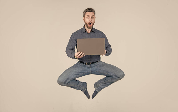 yllättynyt energinen hyppääminen mies liikemies työskennellessään verkossa kannettavan, myynti - Valokuva, kuva