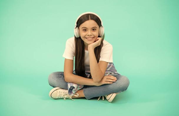χαρούμενο κορίτσι παιδί ακούει μουσική σε ασύρματα ακουστικά, ακουστικά - Φωτογραφία, εικόνα