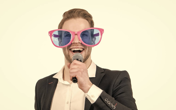 Портрет щасливого професійного чоловіка в кумедних окулярах і офіційний костюм, розмова на мікрофон, шоумен
 - Фото, зображення