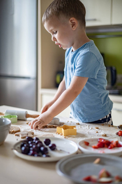 Alegre bebê masculino cozinhar sobremesa de verão caseira com frutas e bagas na cozinha doméstica - Foto, Imagem