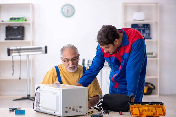 Δύο άνδρες επισκευαστές που εργάζονται στο συνεργείο - Φωτογραφία, εικόνα