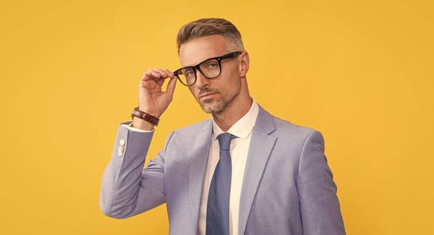 volwassen man in formalwear en bril op gele achtergrond, manager - Foto, afbeelding