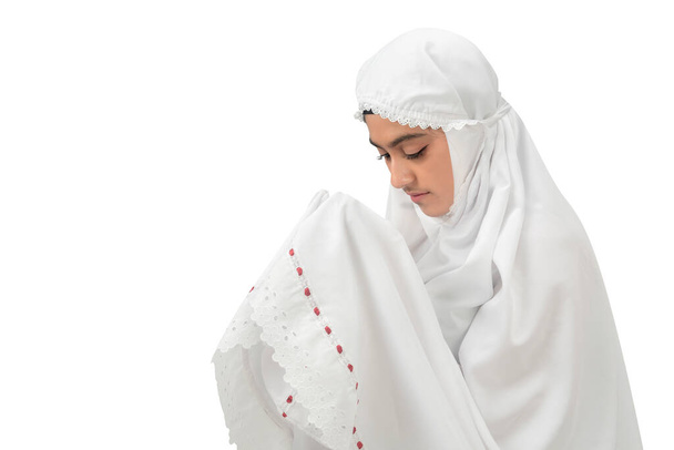 Asian Muslim woman in a veil standing while raised hands and praying isolated over white background - Photo, image