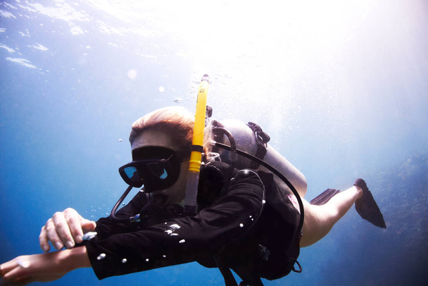 Čas sestoupit. Mladá samice potápěč plovoucí ve vodě, když kontroluje její potápěčský počítač - Copyspace. - Fotografie, Obrázek