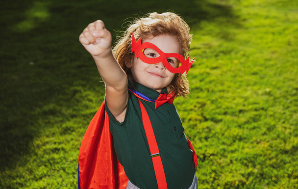 Brave boy in a superhero costume, wearing a red Cape and mask, held out his hand. Cute kid playing superhero. The concept of power and justice. - Foto, Imagem
