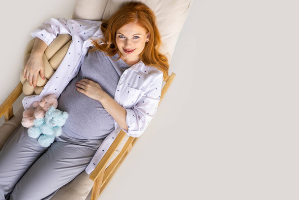 Vista dall'alto felice giovane rossa donna incinta sdraiata su una comoda poltrona - Foto, immagini