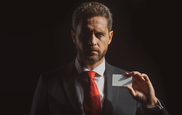 Confident businessman with credit card. Middle-age business man in formalwear suit isolated on black. - Fotó, kép