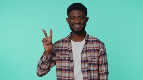 Africký americký usmívající se muž ukazuje znamení vítězství, doufá v úspěch a vítězství, dělá mírové gesto - Záběry, video