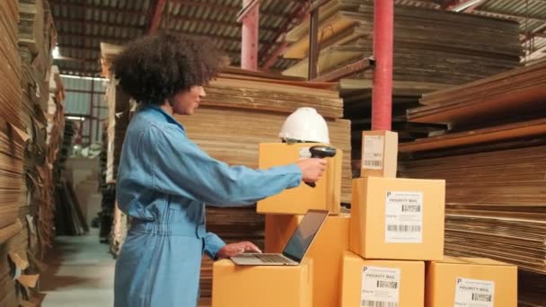 Biztonsági egyenruhás afro-amerikai női munkás vonalkód szkennerrel ellenőrzi a csomagküldő raktárban, papírgyártó üzemben a csomagolóiparban, logisztikai szállítási szolgáltatás. - Felvétel, videó