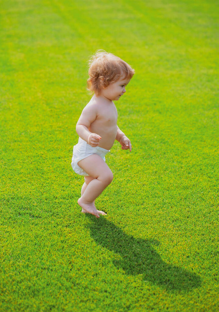 Warm spring time in the park. Baby in beautiful spring green field. First step. - Foto, imagen