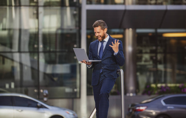 Portrait of excited businessman using laptop outdoor. - Photo, image