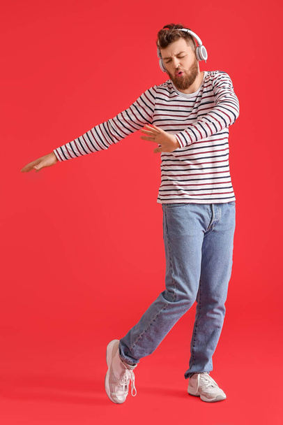 Крутой танцующий молодой человек слушает музыку на цветном фоне - Фото, изображение