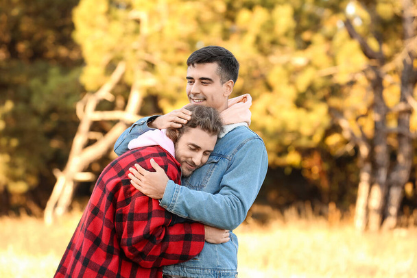 Ευτυχισμένο ζευγάρι γκέι αγκαλιάζονται στο πάρκο φθινόπωρο - Φωτογραφία, εικόνα