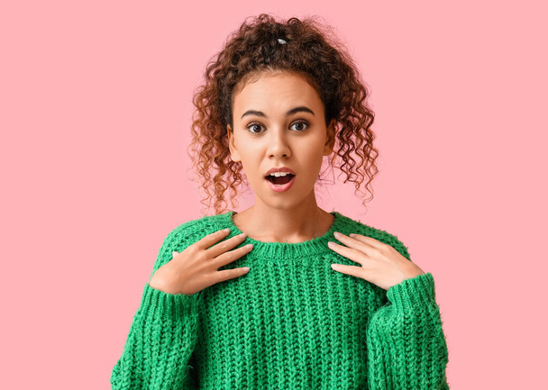 Shocked young African-American woman in green sweater on pink background - Photo, Image