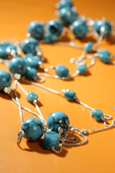Turquoise necklaces over orange background - Fotoğraf, Görsel