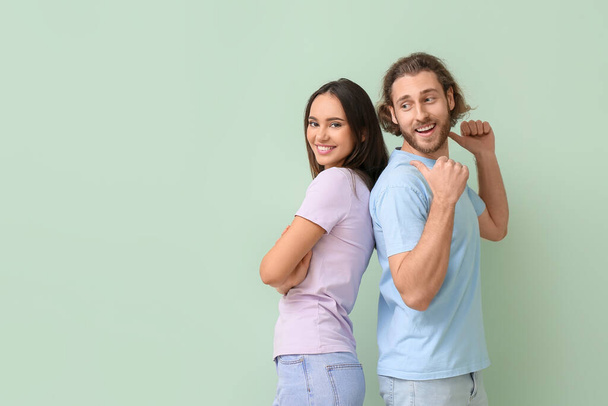 Young couple in stylish t-shirts on green background - Photo, Image