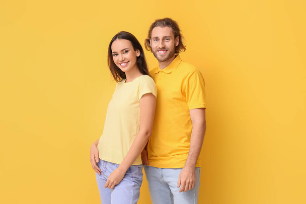Молодая пара в стильных футболках на желтом фоне - Фото, изображение