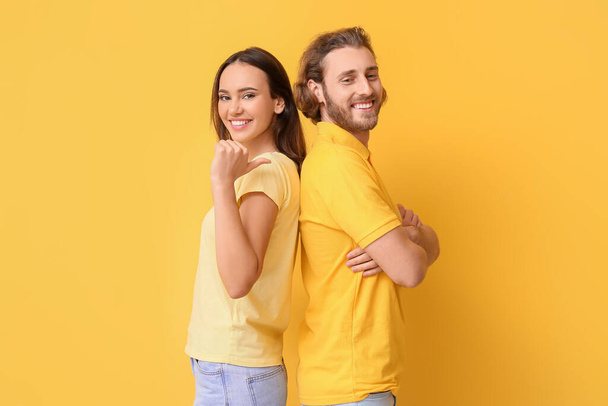 Young couple in stylish t-shirts on yellow background - Foto, Bild
