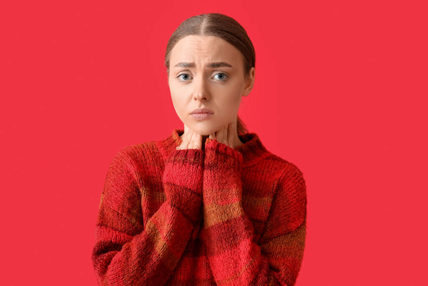 Ill young woman with sore throat on red background - Фото, зображення