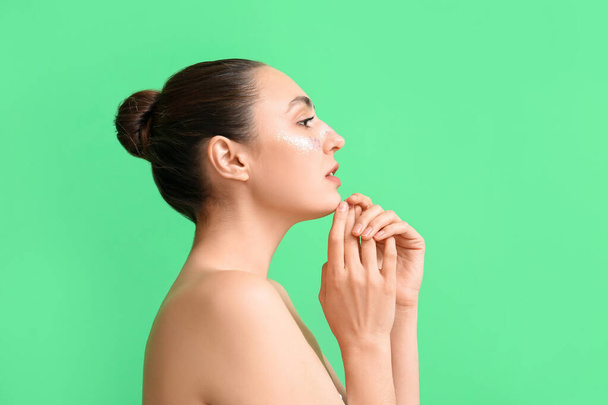 Γυναίκα με δημιουργικό μακιγιάζ σε πράσινο φόντο - Φωτογραφία, εικόνα