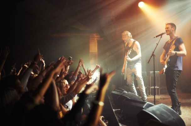 Shot of a crowd of music fans reaching up at a guitarist on stage. This concert was created for the sole purpose of this photo shoot, featuring 300 models and 3 live bands. All people in this shoot - Foto, immagini