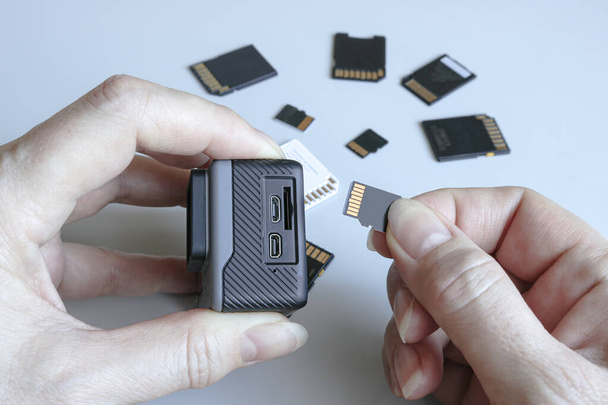 Caméra d'action et carte mémoire microSD dans les mains sur le dos d'autres cartes mémoire SD. Contexte des gadgets et des appareils numériques. - Photo, image