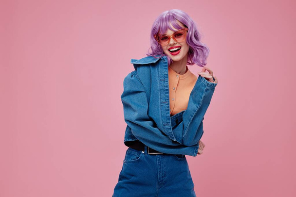 Mujer joven positiva pelo morado gafas de moda denim ropa color fondo inalterado - Foto, Imagen