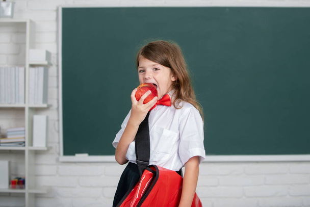 Kids education and knowledge. Student kids. Portrait of lovely girl wuth red apple in classroom. - Photo, Image