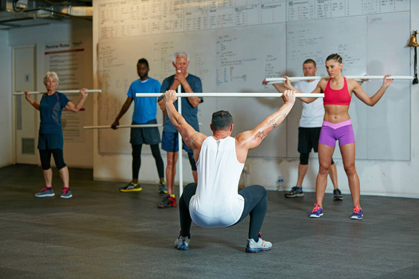 Vede svou třídu. Shot of a fitness group working out at the gym. - Fotografie, Obrázek