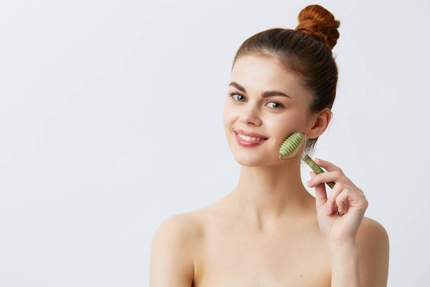 woman with massage roller anti aging facial treatment isolated background. High quality photo - 写真・画像