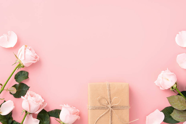 Valentine's Day design concept background with pink rose flower and wrapped kraft gift box on pink table background. - Фото, зображення