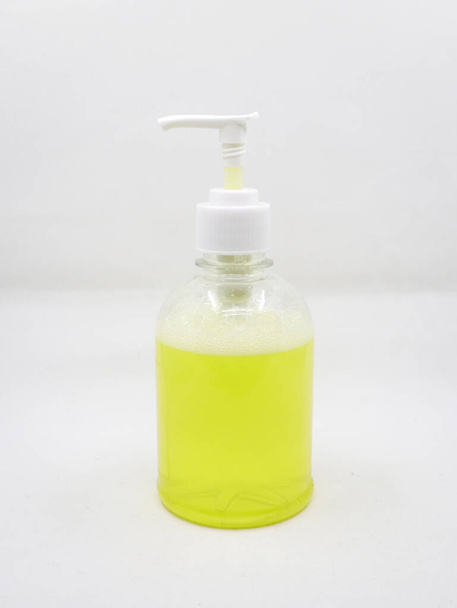 dispensador de jabón tipo prensa con solución de jabón amarillo para la limpieza de manos utilizadas en lavabos aislados en un fondo blanco - Foto, Imagen