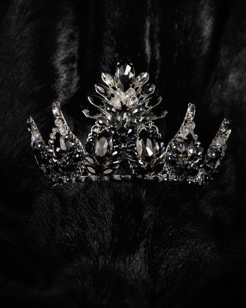 красивая серебряная корона с черным камнем для мисс красоты на черном блестящем фоне, крупным планом - Фото, изображение