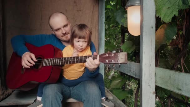 Papá toca una guitarra acústica para su hijo pequeño. Decoración antigua, retro - Metraje, vídeo
