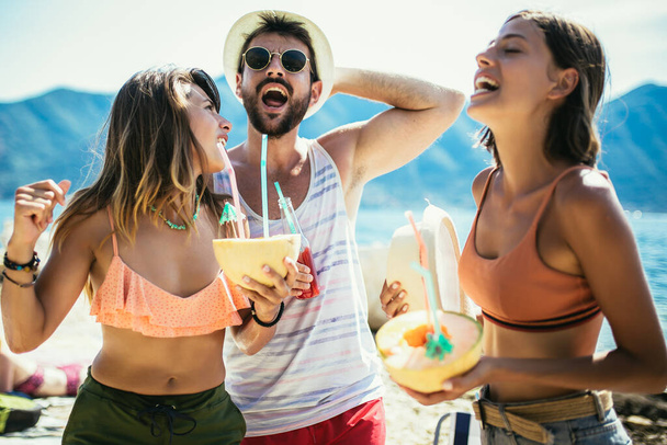 Groupe d'amis s'amuser sur la plage en dansant et en buvant des cocktails.  - Photo, image