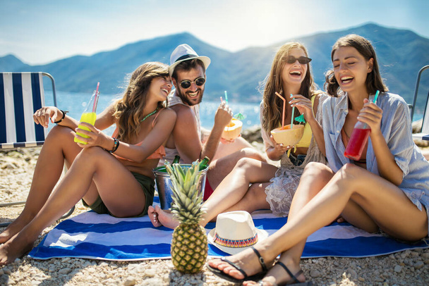 Amigos felices divirtiéndose con cócteles tropicales en la fiesta de playa. Concepto de viajes y vacaciones de verano. - Foto, imagen