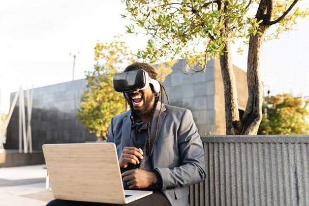 Afrikanischer Geschäftsmann lächelnd mit Virtual-Reality-Brille in seiner Freizeit im Park - Foto, Bild