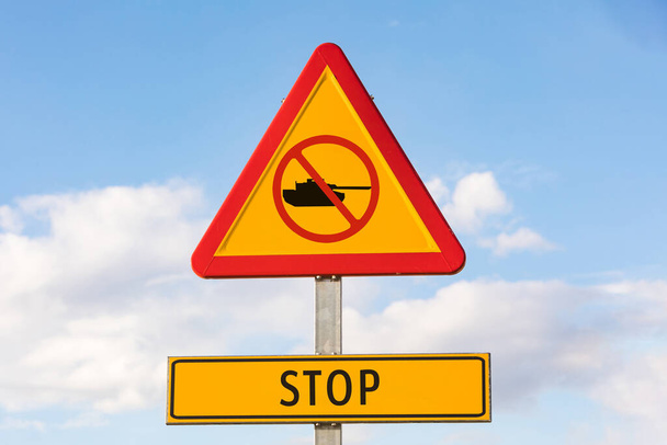 Gevaarlijk verkeerssignaal met een tank met een verboden signaal en een bord dat zegt: 'STOP', met de lucht op de achtergrond. Oorlogsconcept, Oekraïne, Rusland en oorlogsconflict. - Foto, afbeelding