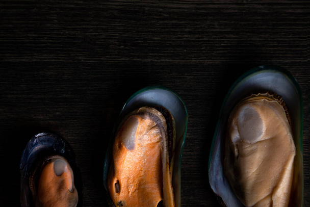 cooked mussels of different sizes on a wooden background - Valokuva, kuva
