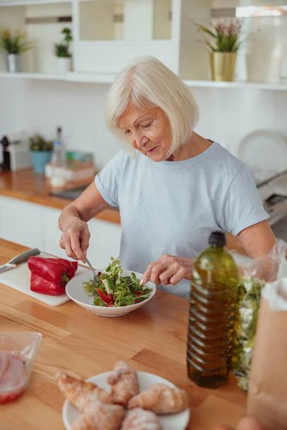 Obrázek starší ženy vaření v kuchyni doma - Fotografie, Obrázek