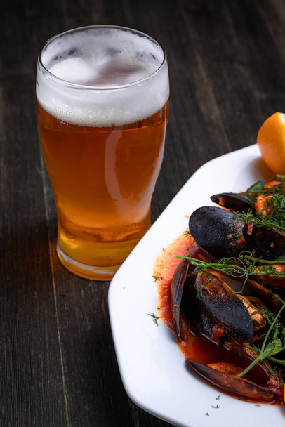 beer with mussels in tomato sauce with microgreens and lemon, on a wooden background - Fotoğraf, Görsel