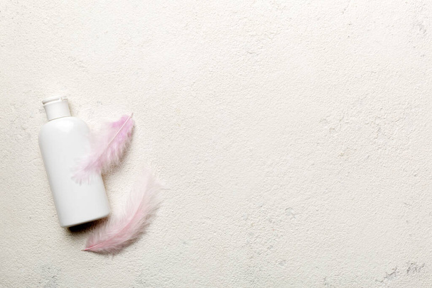 Комплект сывороток по уходу за кожей на розовом пастельном фоне со страусиными перьями. Спа косметический продукт, банку крема, макет бренда, вид сверху с копировальным пространством. - Фото, изображение