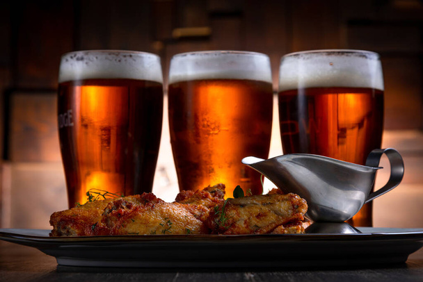 fried chicken wings served with beer on a dark background - Foto, Bild