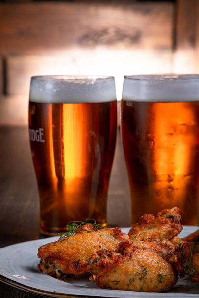 fried chicken wings served with beer on a dark background - Фото, изображение
