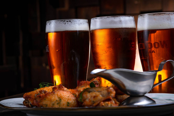 fried chicken wings served with beer on a dark background - Foto, Imagem