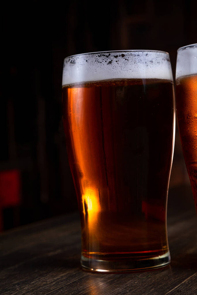 a glass of foamy beer on a dark background - Photo, image